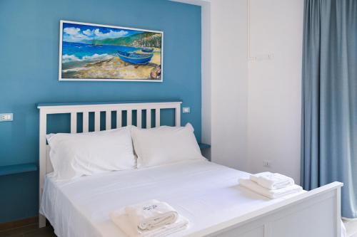 a bedroom with a white bed with a blue wall at Signora Tita B&B Chianalea - Scilla in Scilla