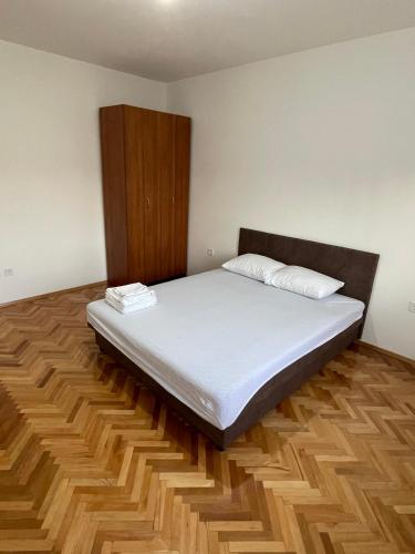 1 dormitorio con 1 cama y armario de madera en Entire spacious apartment with free parking, en Podgorica