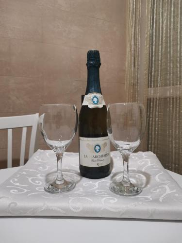 a bottle of wine and two wine glasses on a table at Apartman Caroline in Čačak