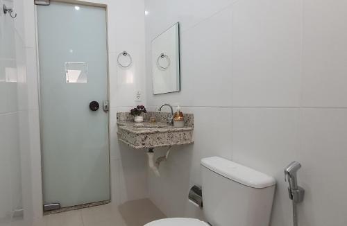 a white bathroom with a toilet and a sink at Apartamento no centro próximo a Jk in Palmas