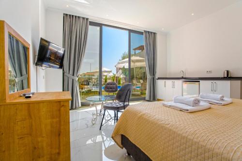 a bedroom with a bed and a tv and a balcony at Nur Suites & Hotels in Kalkan