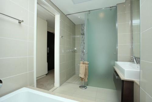 baño blanco con ducha y lavamanos en Sandton Skye Exclusive Apartment, en Johannesburgo