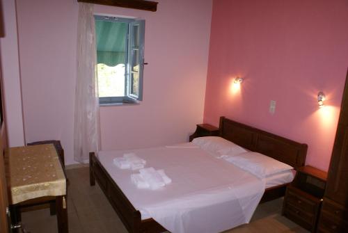 a bedroom with a bed with white sheets and a window at Katafigio Village in Kotrónion