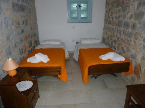 two beds in a room with orange sheets and towels at Katafigio Village in Kotrónion