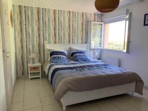 LʼÎle-dʼOlonne的住宿－les mouettes，一间卧室配有一张带蓝色枕头的床和一扇窗户。