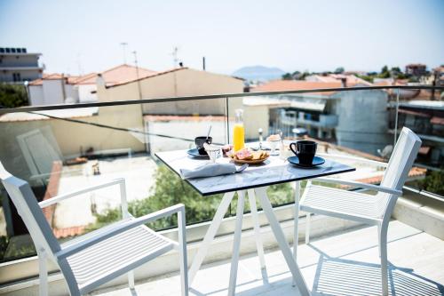 a table and two chairs on a balcony with food on it at Kali Thea Suites in Neos Marmaras