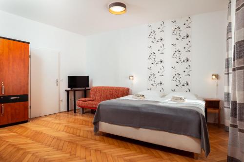a bedroom with a bed and a red chair at Penzion Pod Lipo in Ljubljana
