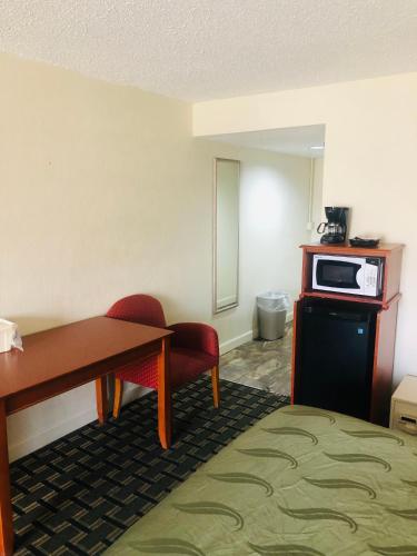 a hotel room with a desk and a microwave at Quail Inn and Suites - Myrtle Beach in Myrtle Beach