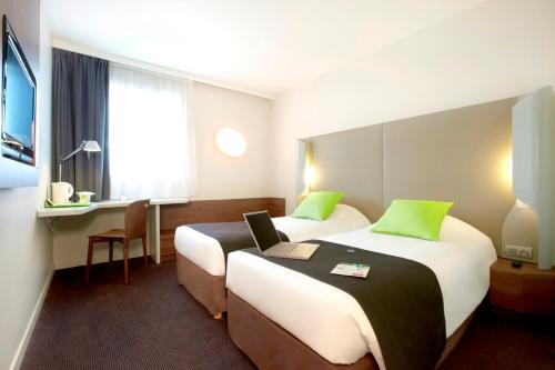 a hotel room with two beds and a desk at Campanile Montbéliard - Sochaux in Sochaux