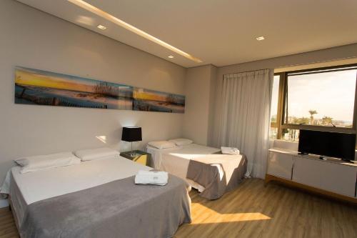 um quarto de hotel com duas camas e uma televisão de ecrã plano em Locking's Santo Agostinho 1 em Belo Horizonte