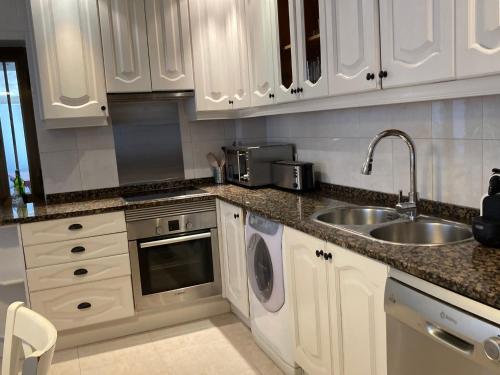a kitchen with white cabinets and a sink at Los Cedros, gran chalet con piscina y apartamento en Navacerrada in Navacerrada
