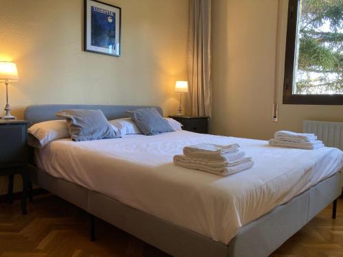 a bedroom with a large bed with towels on it at Gran chalet con piscina y apartamento en Navacerrada in Navacerrada