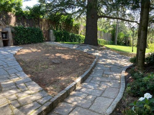 a garden with a tree and a stone walkway at Los Cedros, gran chalet con piscina y apartamento en Navacerrada in Navacerrada