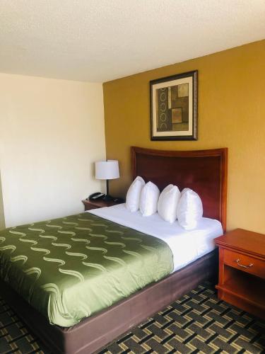 a hotel room with a bed with a green blanket at Quail Inn and Suites - Myrtle Beach in Myrtle Beach