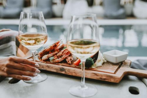 two glasses of wine next to a plate of food at Ikaros Suites in Amoudara Herakliou