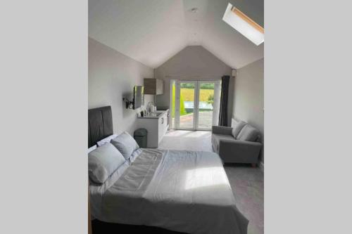 a bedroom with a large bed and a couch at The Forest Chalet - Stunning Studio Apartment in Ballycastle