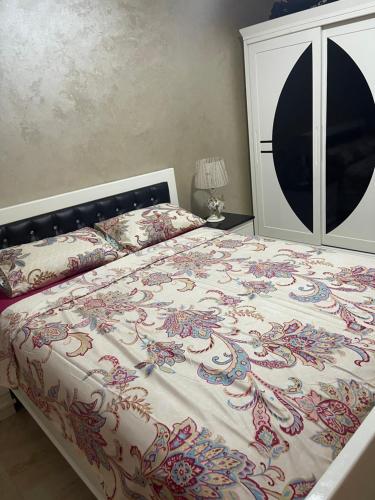 a bedroom with a bed with a floral bedspread at Location appartement Alhoceima in Al Hoceïma