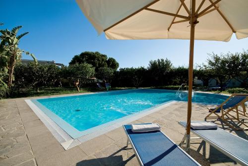 una piscina con sombrilla, 2 sillas y una mesa en Appartamenti Le Pleiadi - Succhivo d'Ischia, en Isquia