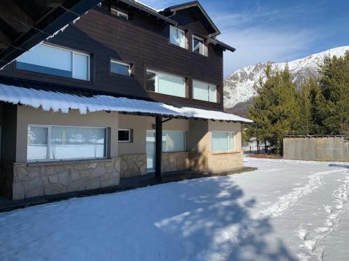 a house with snow on the ground in front of it at CATEDRAL SUITES in San Carlos de Bariloche