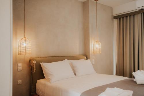 a bedroom with a bed with white pillows and two lights at elia boutique hotel in Parga