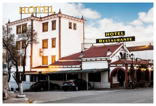 un hotel con coches estacionados frente a un edificio en El Mesón de Despeñaperros, en Santa Elena