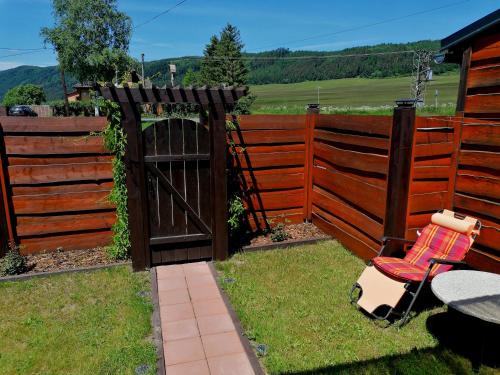 a fence with a table and a chair in a yard at Ranch pod lesom Slovensky Raj in Spišský Štiavnik