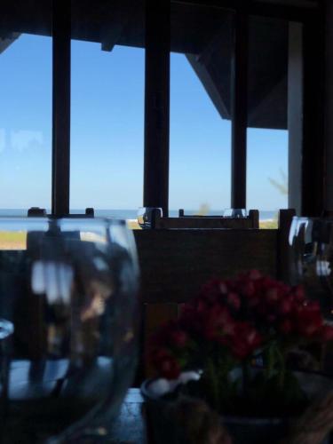 a table with a vase of flowers and a window at Pousada Caminho do Mar MADHOUZE in Garopaba