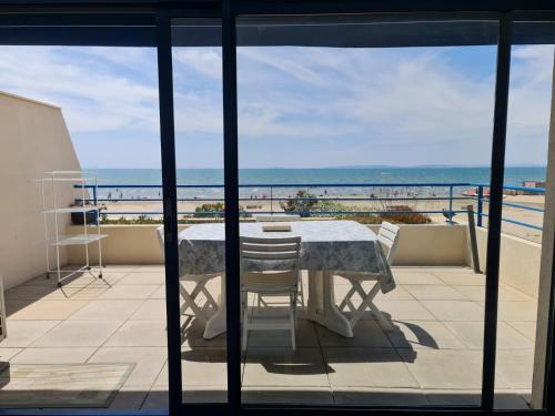 uma mesa e cadeiras numa varanda com vista para o oceano em Exceptionnel, sur la plage en front de mer em Le Grau-du-Roi