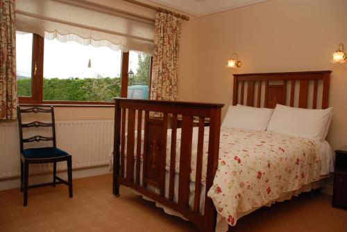 a bedroom with a bed and a chair and a window at Cradog Farmhouse B&B in Urlingford