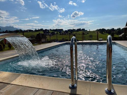 a swimming pool with a water fountain at Apartamenty Liliowe SPA & Wellness in Murzasichle