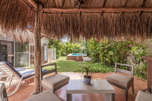 a patio with a table and chairs and a straw umbrella at Casa Nona Rosa in Cancún
