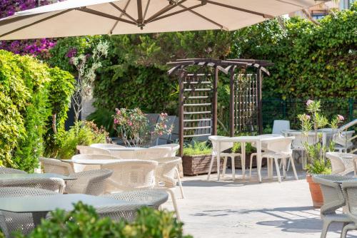 a patio with tables and chairs and an umbrella at Playas del Rey in Santa Ponsa