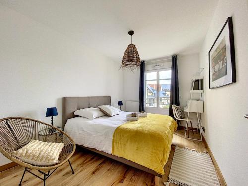 a bedroom with a bed and a chair and a window at L'ancre Marine YourHostHelper in Deauville
