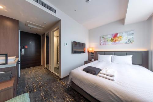 a bedroom with a white bed and a television at Hotel Forza Nagoya Sakae in Nagoya