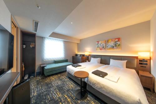 名古屋市にあるホテルフォルツァ名古屋栄の大型ベッドとテレビが備わるホテルルームです。