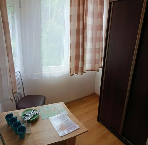 a table with plates and cups on it next to a window at DW Bukówka in Karpacz
