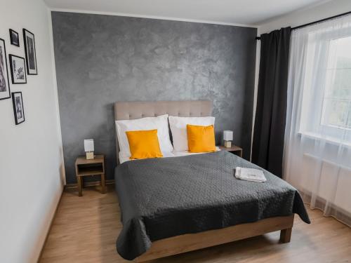 a bedroom with a large bed with two orange pillows at Wellness Apartmány Panorama in Luhačovice