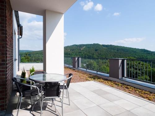 a patio with a glass table and chairs on a balcony at Wellness Apartmány Panorama in Luhačovice