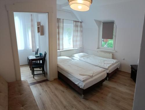 a bedroom with a bed and a table and windows at DW Bukówka in Karpacz