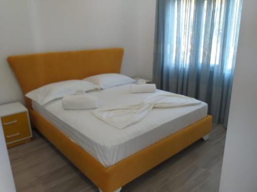 un letto con lenzuola e cuscini bianchi in una camera da letto di Villa Ermis a Dhërmi