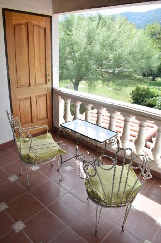 a balcony with two chairs and a table and a window at Estancia Santa Leocadia in Bialet Massé