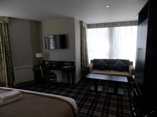 a hotel room with a couch and a desk at Best Western Plus Pinewood Manchester Airport-Wilmslow Hotel in Handforth