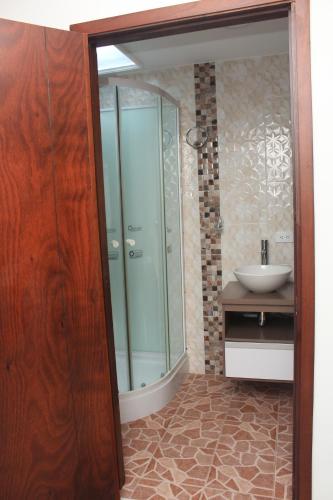 a bathroom with a glass shower and a sink at Hotel Velices in Buga