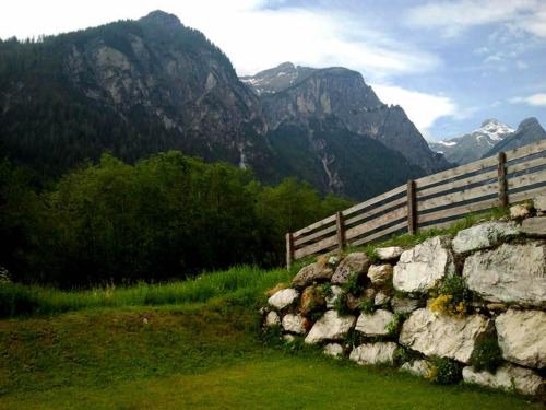 a stone wall with a fence and mountains in the background at Ferienwohnung Familie Tost in Trins