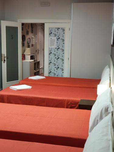 two beds in a room with red sheets at Pensión El Espolón in Logroño