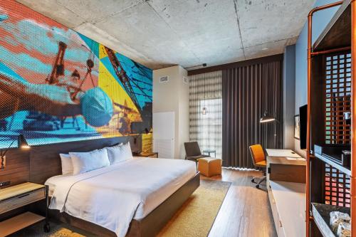 a hotel room with a bed and a painting on the wall at Hotel Indigo Tulsa DWTN/Entertainment Area in Tulsa