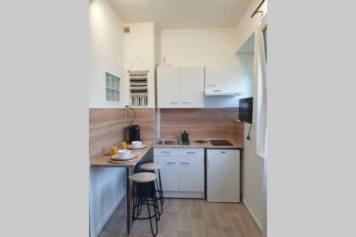 une cuisine avec des armoires blanches et une table et des chaises dans l'établissement Studio COSY en bord de mer, à Dunkerque