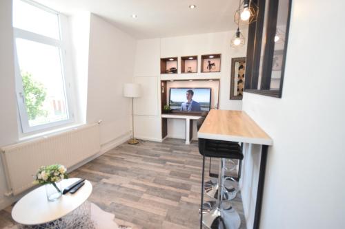 un salon avec une télévision et une table dans l'établissement DESIGN APPART - HYPER CENTRE - TRAM - FREE WIFI - leRelaisdOdile21, à Valenciennes