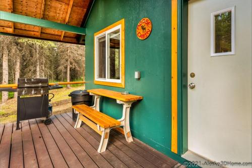 a cabin with a bench and a grill on a deck at Backwoods Lodge in Cantwell