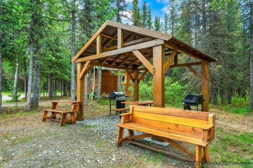 a wooden pavilion with two benches and a grill at Backwoods Lodge in Cantwell